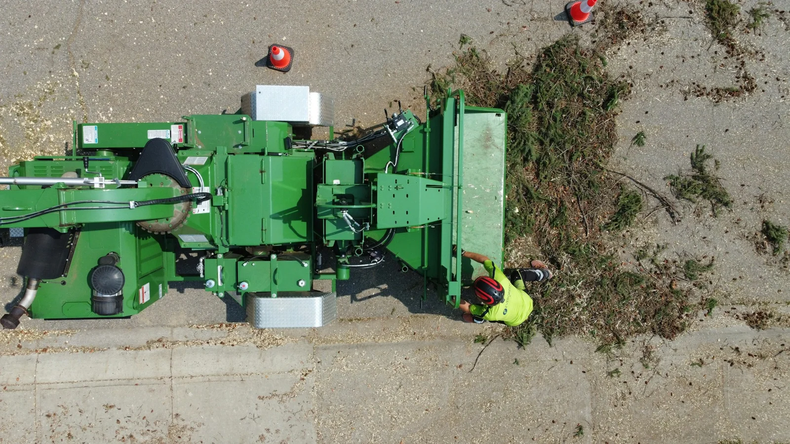 Operator loading plant residues into a commercial wood chipper — representative organic-material preparation
